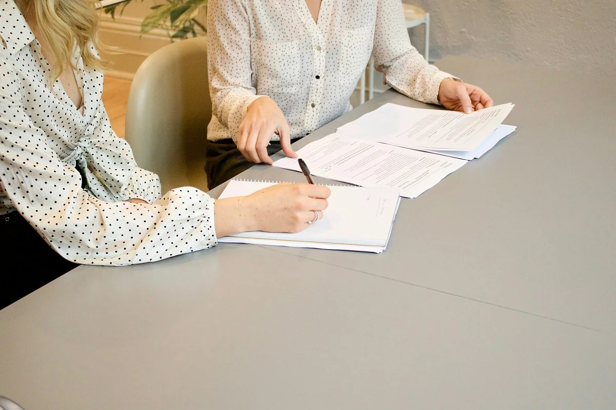 Duas pessoas revisando documentos sobre a mesa